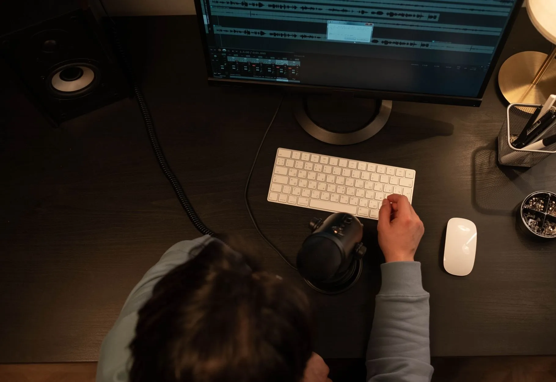 A person at a desk seen from above, one hand on a white keyboard